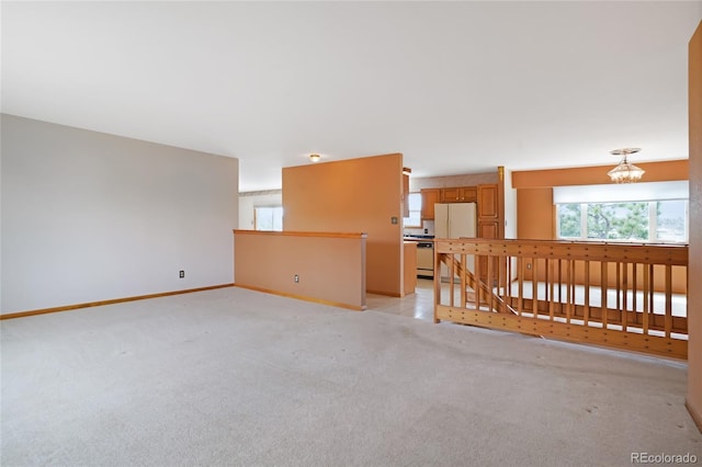 empty room with baseboards, an inviting chandelier, and light carpet