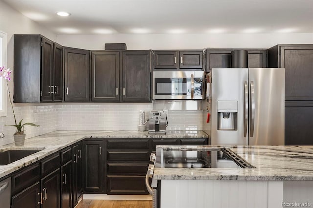 kitchen with backsplash, sink, light stone countertops, light hardwood / wood-style floors, and stainless steel appliances