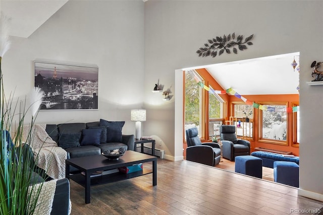 living room with hardwood / wood-style floors, high vaulted ceiling, and a baseboard radiator