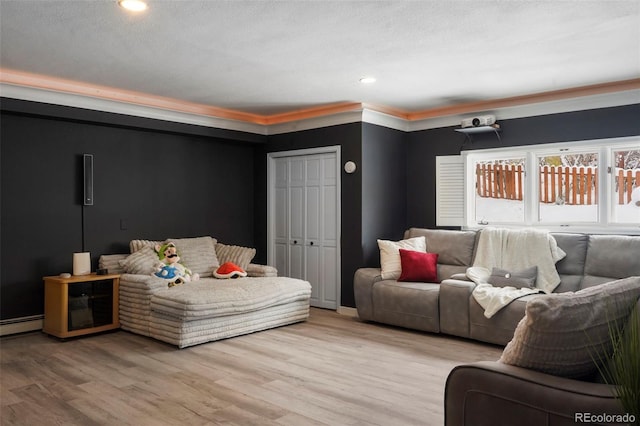 interior space featuring crown molding, light hardwood / wood-style flooring, a textured ceiling, and a baseboard heating unit