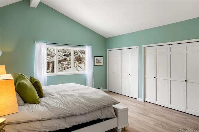 bedroom with vaulted ceiling with beams, light hardwood / wood-style floors, and multiple closets