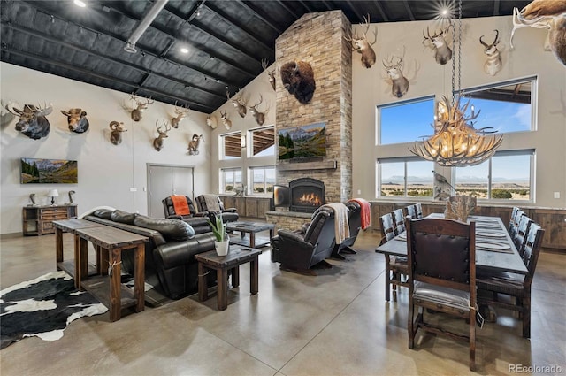 living room with a stone fireplace, high vaulted ceiling, and concrete floors