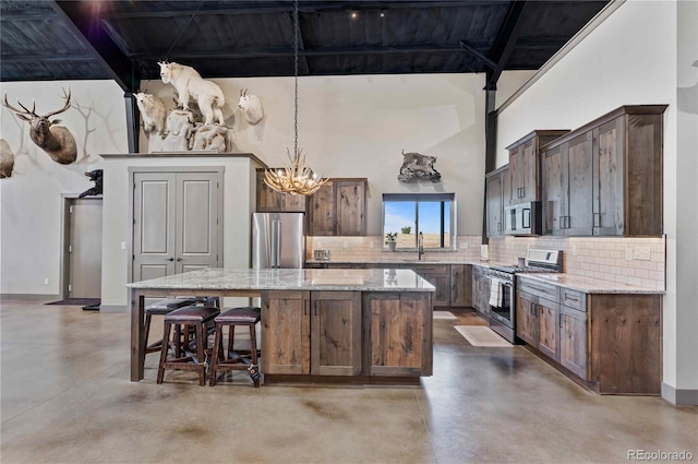 kitchen featuring decorative backsplash, a center island, light stone counters, and appliances with stainless steel finishes