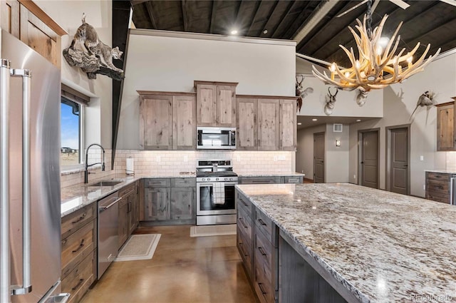 kitchen featuring light stone counters, stainless steel appliances, sink, a chandelier, and concrete floors