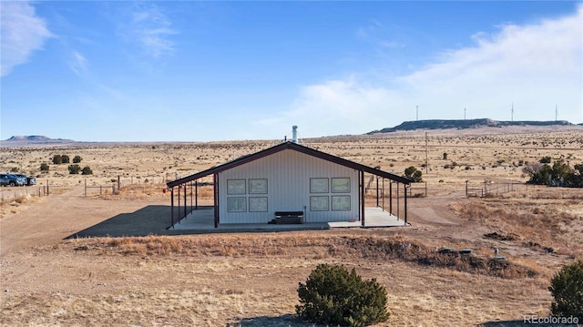 back of property with a mountain view and a rural view