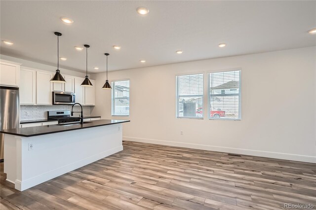6874 Zuni Ct, Denver, CO 80221 - kitchen featuring appliances with stainless steel finishes, a sink, dark countertops, light wood-type flooring, and recessed lighting