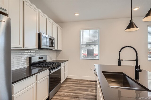 6874 Zuni Ct, Denver, CO 80221 - kitchen with appliances with stainless steel finishes, a sink, dark countertops, light wood-style flooring, and backsplash