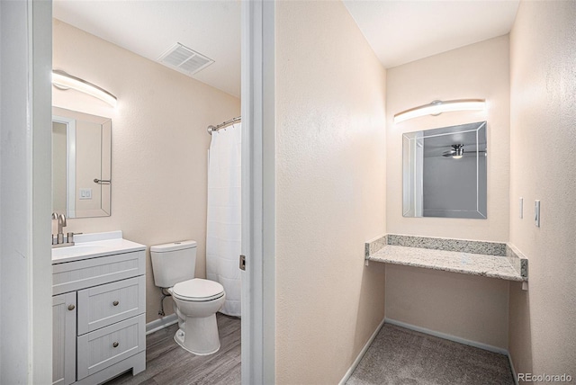 bathroom with a shower with shower curtain, hardwood / wood-style floors, vanity, and toilet