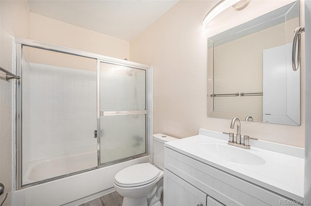 full bathroom featuring wood-type flooring, vanity, combined bath / shower with glass door, and toilet