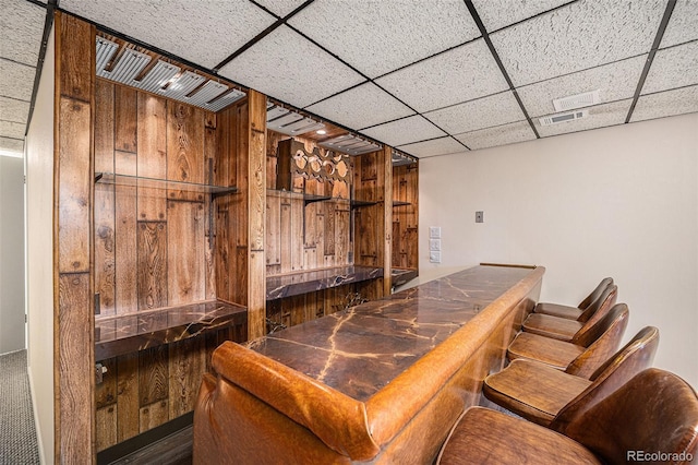 bar with a paneled ceiling and wood walls