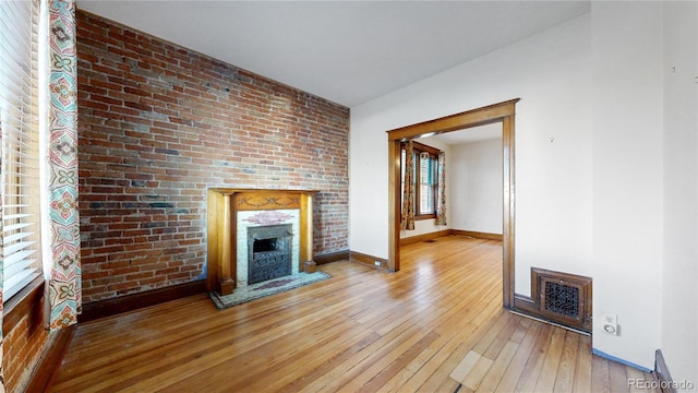 unfurnished living room with light hardwood / wood-style floors and brick wall