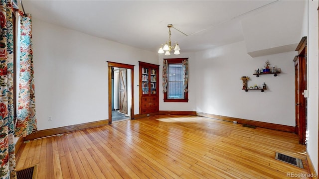 unfurnished room featuring hardwood / wood-style flooring and a notable chandelier