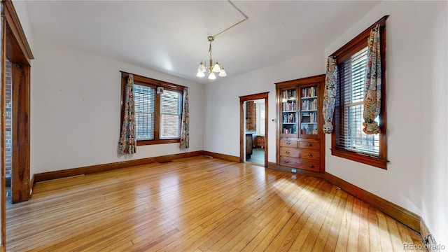 unfurnished room featuring light hardwood / wood-style floors, a healthy amount of sunlight, and a notable chandelier