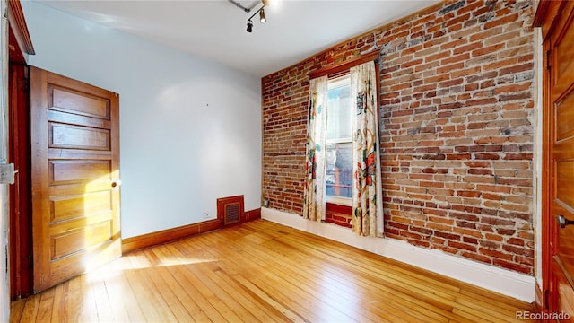 empty room featuring light hardwood / wood-style flooring and brick wall