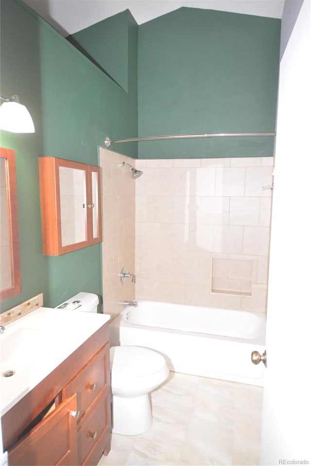 full bathroom featuring vanity, tiled shower / bath combo, and toilet