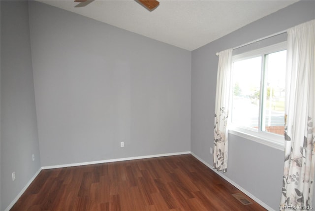 unfurnished room with ceiling fan and dark wood-type flooring