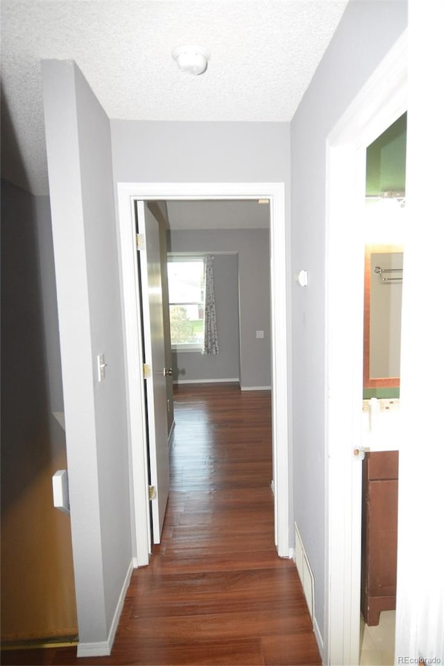 corridor with dark hardwood / wood-style floors and a textured ceiling