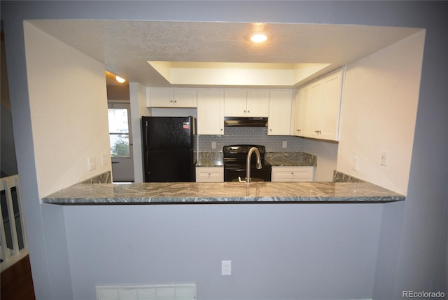 kitchen featuring dark stone countertops, white cabinetry, and black appliances