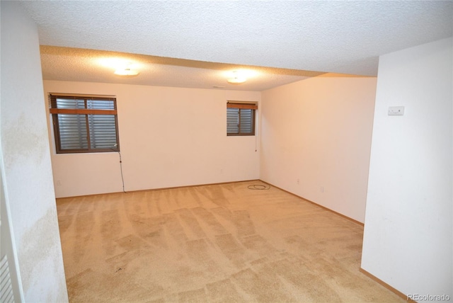 spare room with light carpet and a textured ceiling