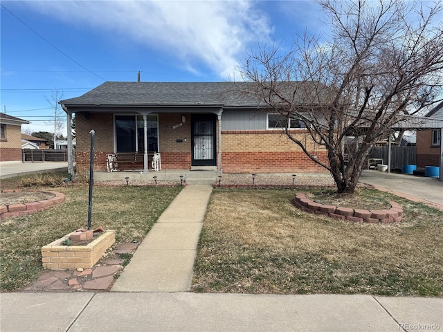 view of front facade featuring brick siding, a shingled roof, fence, a front yard, and covered porch