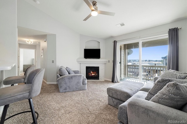 carpeted living room featuring ceiling fan, lofted ceiling, and a high end fireplace