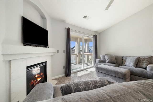 living room featuring vaulted ceiling, light carpet, and a high end fireplace