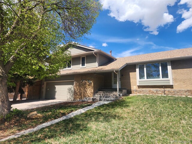 tri-level home with an attached garage, a front yard, driveway, and brick siding