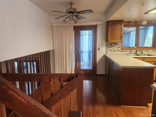 kitchen featuring ceiling fan, tasteful backsplash, light wood-type flooring, light countertops, and a sink