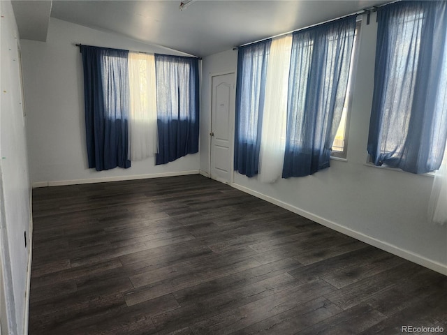 empty room featuring baseboards, vaulted ceiling, and wood finished floors