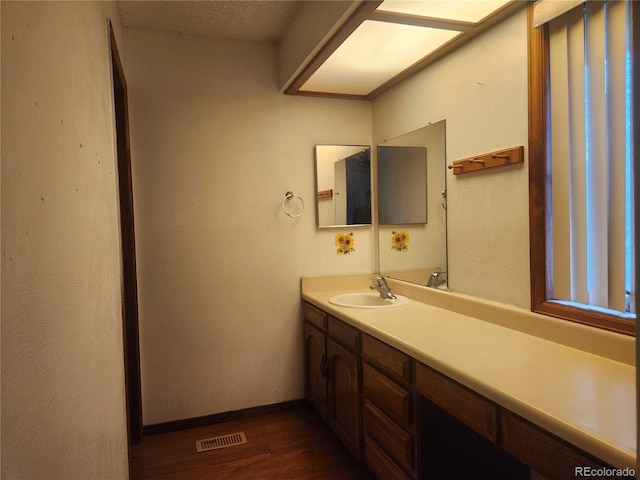 bathroom with vanity, baseboards, wood finished floors, and visible vents