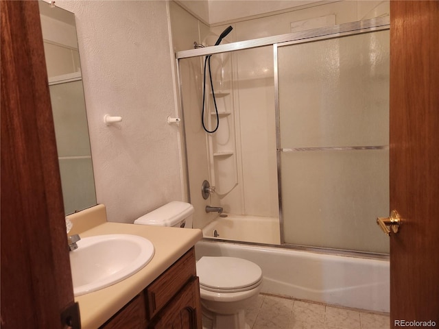 full bath featuring vanity, a textured wall, combined bath / shower with glass door, and toilet