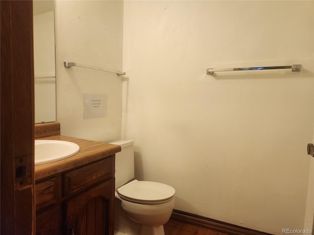 half bathroom featuring vanity, toilet, and wood finished floors