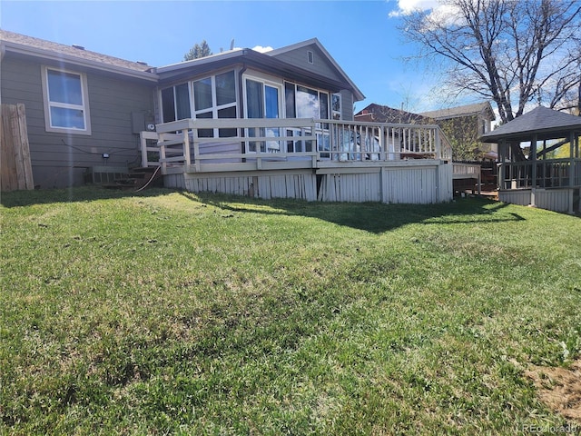 rear view of property featuring a sunroom, a wooden deck, a yard, and a gazebo