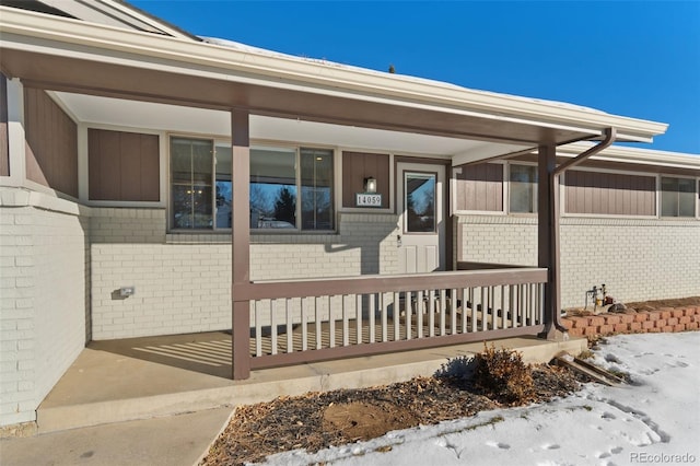 snow covered property entrance featuring a porch