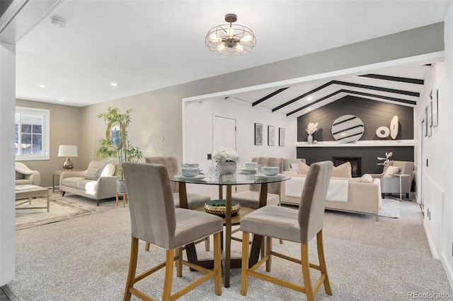 carpeted dining room with lofted ceiling with beams and a chandelier