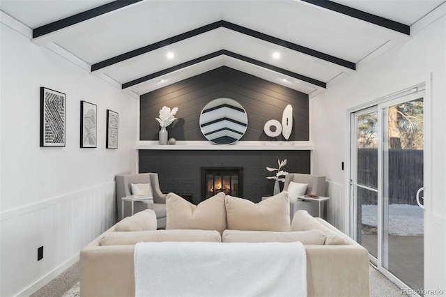 living room with lofted ceiling with beams, a brick fireplace, and light colored carpet