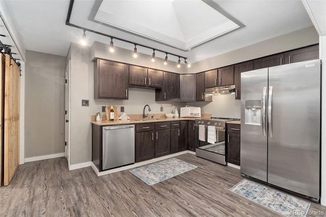 kitchen with sink, hardwood / wood-style flooring, stainless steel appliances, dark brown cabinetry, and a barn door