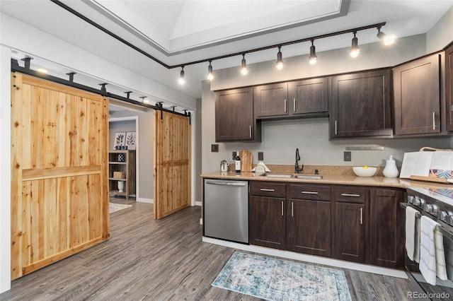 kitchen with sink, wood-type flooring, a barn door, and appliances with stainless steel finishes