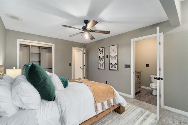 bedroom featuring ceiling fan, ensuite bath, light carpet, and a closet