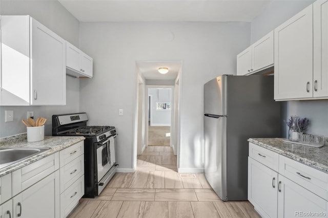 kitchen featuring white cabinetry, light stone countertops, and appliances with stainless steel finishes