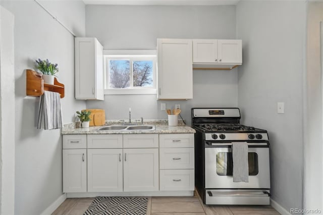 kitchen featuring light stone countertops, stainless steel range with gas cooktop, sink, and white cabinets