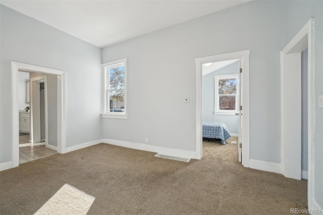 unfurnished bedroom featuring vaulted ceiling and light carpet