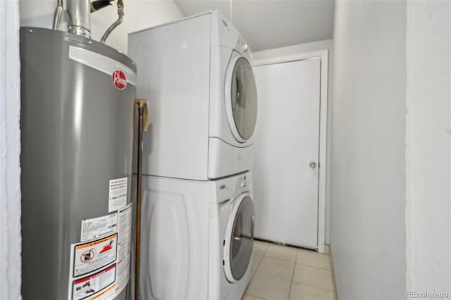 washroom with light tile patterned floors, stacked washer and clothes dryer, and water heater