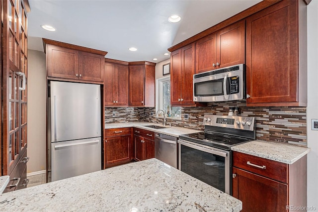 kitchen with stainless steel appliances, sink, and light stone counters