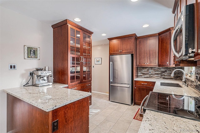 kitchen with stainless steel appliances, light stone countertops, sink, and backsplash