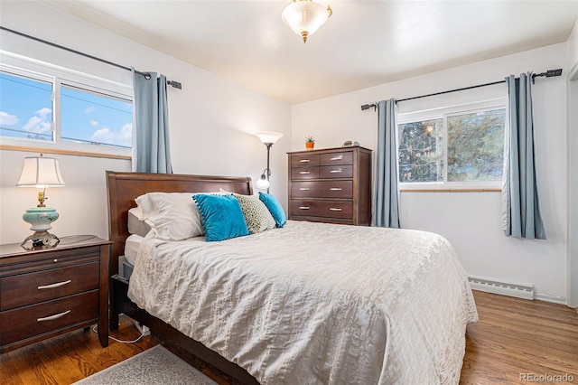 bedroom with baseboard heating and hardwood / wood-style flooring