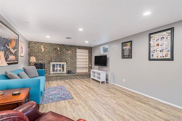 living room with a brick fireplace, built in features, and light wood-type flooring