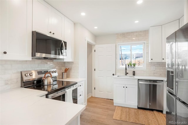 kitchen featuring white cabinetry, sink, appliances with stainless steel finishes, and light hardwood / wood-style flooring