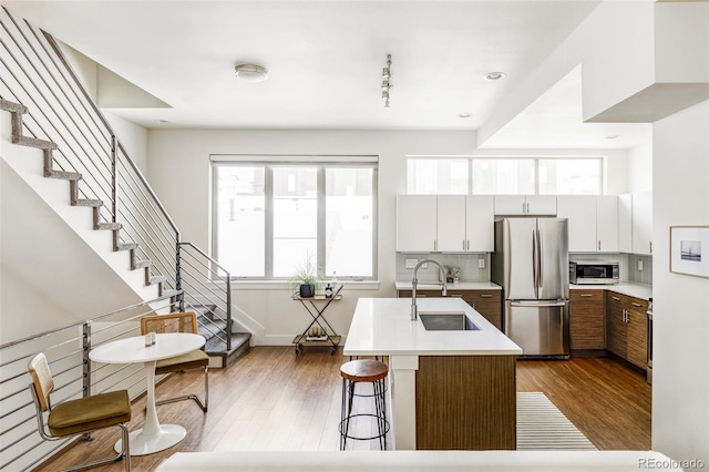 kitchen featuring sink, white cabinetry, an island with sink, stainless steel appliances, and decorative backsplash