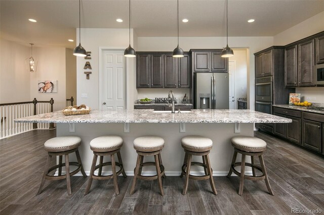 4722 S Netherland St, Centennial, CO 80015 - kitchen featuring appliances with stainless steel finishes, dark wood-style floors, recessed lighting, a kitchen breakfast bar, and dark brown cabinetry